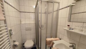 A bathroom with a glass-enclosed shower, a toilet, a sink, and a towel rack.