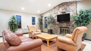 A spacious living room with leather sofas, a wooden coffee table, and a stone fireplace. - Super 8 Billings (Billings)