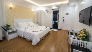 Une chambre à coucher comprenant un lit, une table de chevet, un appareil de climatisation et un téléviseur fixé au mur.
