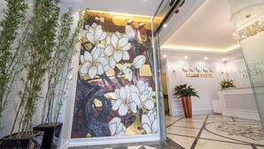 Un hall d’entrée agrémenté d’un mur en mosaïque, de plantes en pot et d’un comptoir d’accueil.