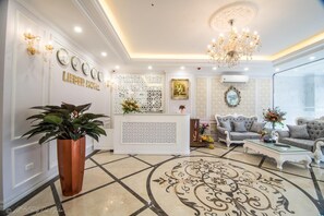A hotel lobby with a reception desk, seating area, and decorative elements like clocks and a chandelier. - Lieber Hotel (Hanoi)