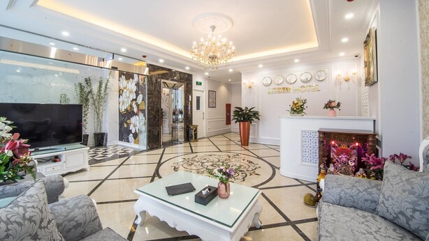 Un hall d’hôtel spacieux, doté d’un grand téléviseur, de sièges confortables, d’une cheminée décorative et d’un lustre.