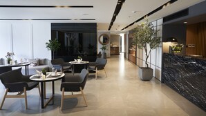 Een modern interieur met een eetgedeelte met ronde tafels en stoelen, een grote potplant en een accentmuur van zwart marmer.