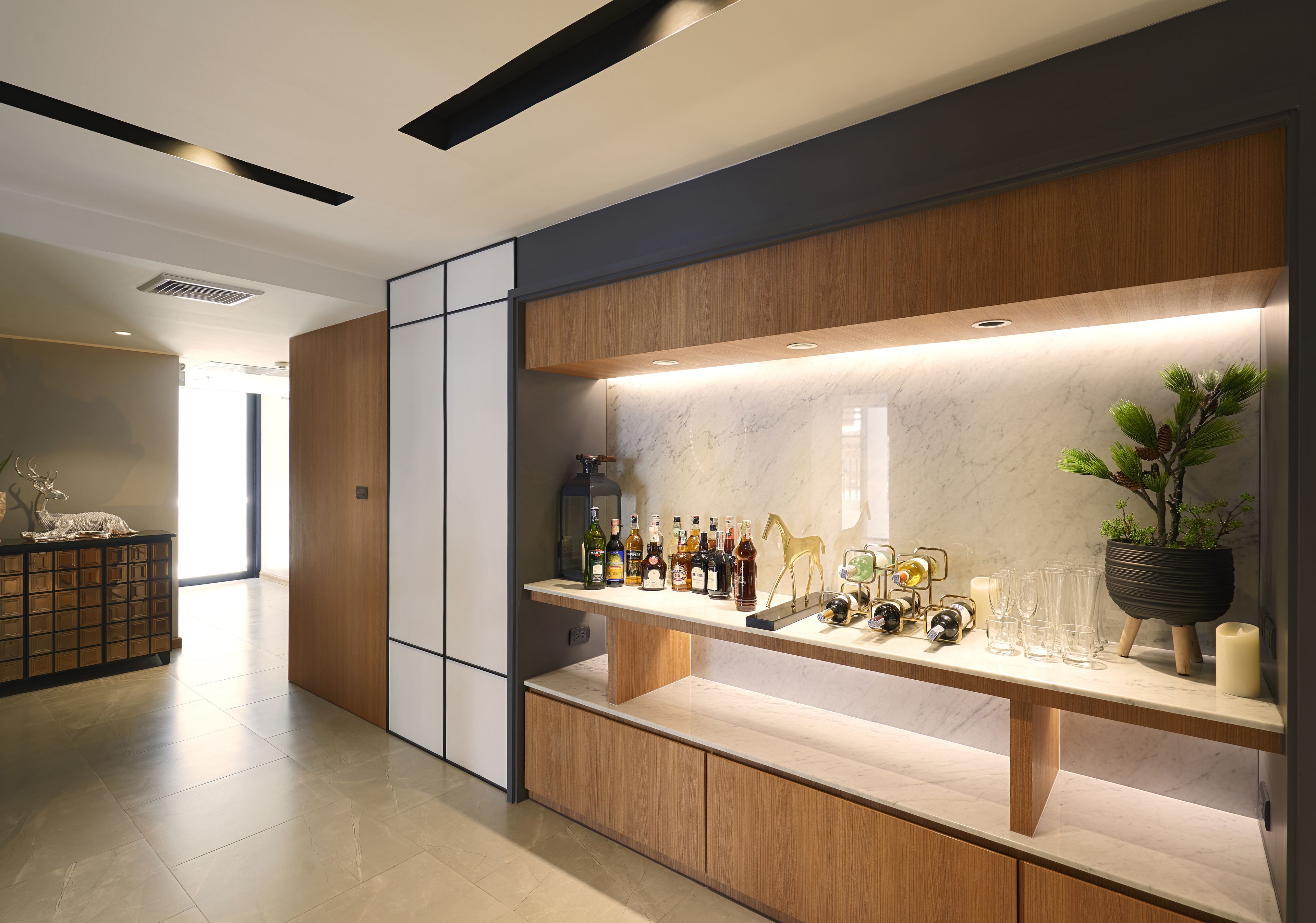 A modern kitchen with a marble countertop, wooden cabinets, and a built-in wine rack.