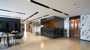 A modern lobby with a reception desk, seating area, and a marble wall. - Has Pattaya (Pattaya)