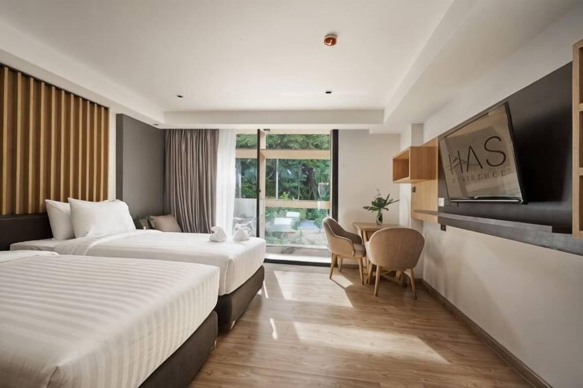 Une chambre d’hôtel moderne équipée de deux lits, d’un bureau, d’une chaise et d’un téléviseur.