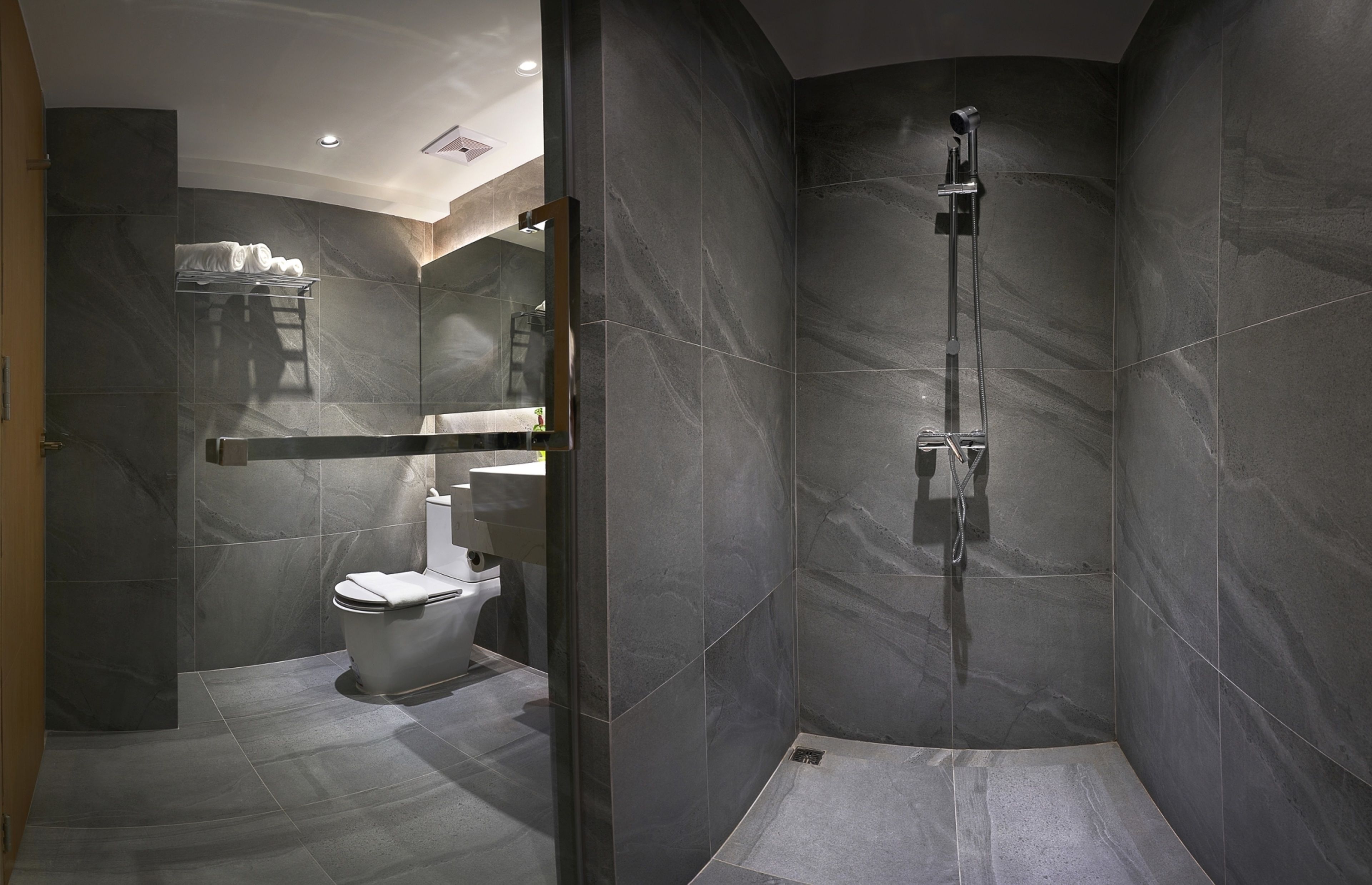 A modern bathroom with a shower, toilet, and a towel rack.