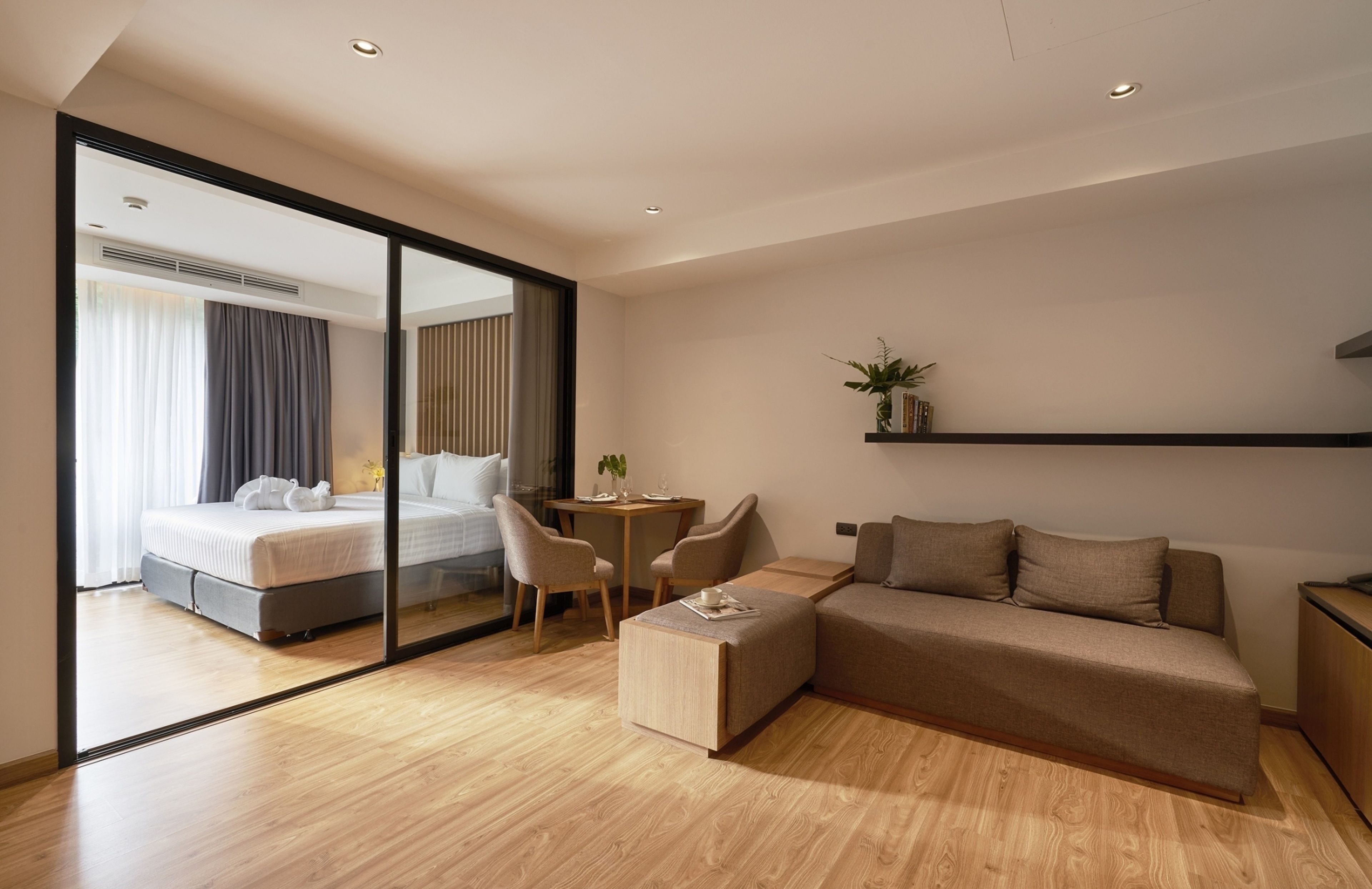 Una habitación de hotel moderna con una cama grande, un sofá, una mesita y un espejo.