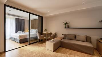 Una habitación de hotel moderna con una cama grande, un sofá, una mesita y un espejo.