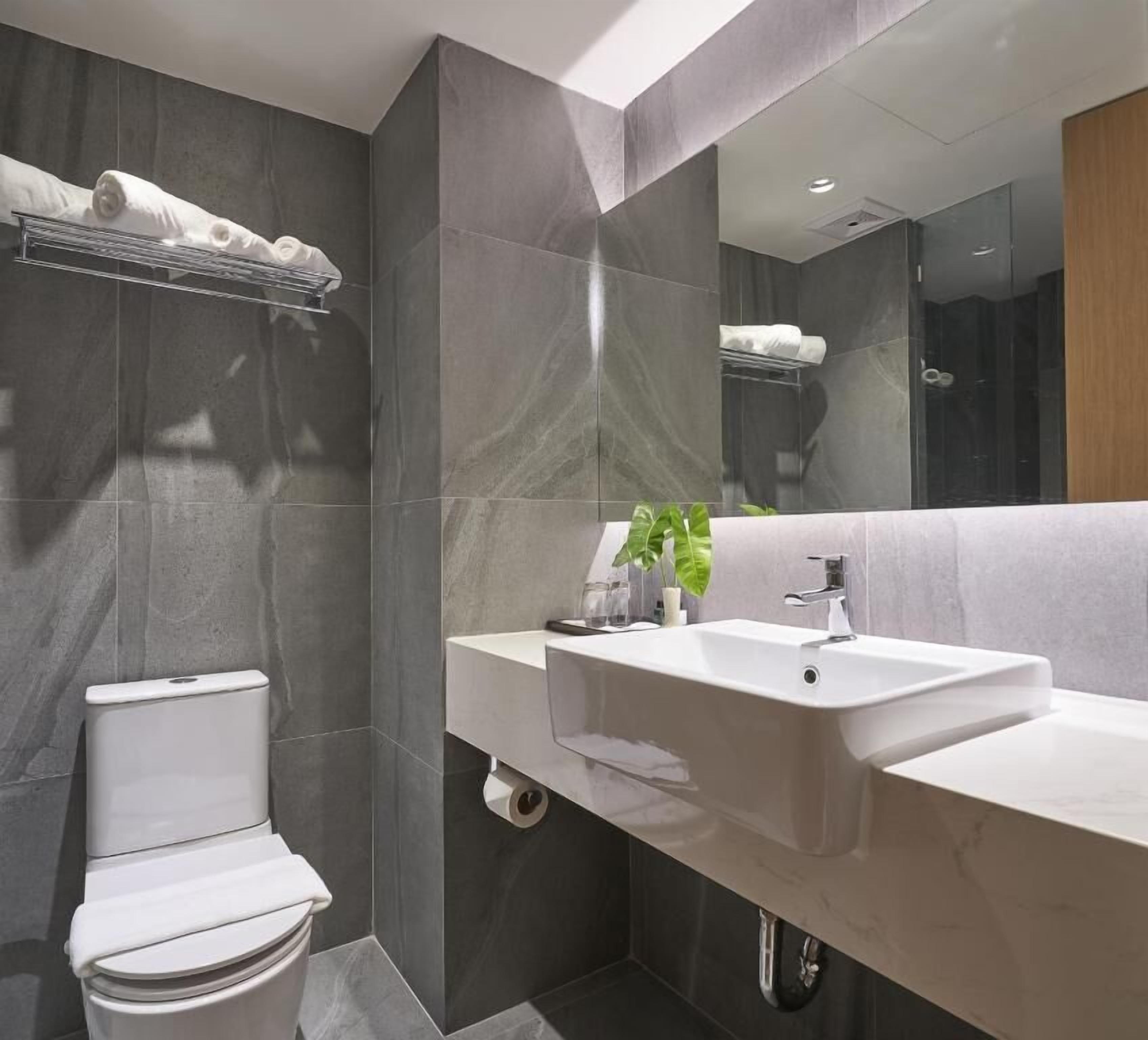 Une salle de bain moderne avec des toilettes, un lavabo et un miroir.