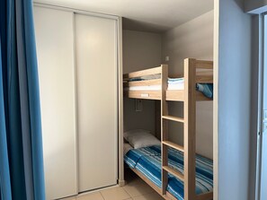 Quarto com uma cama beliche, guarda-roupa e cortina.