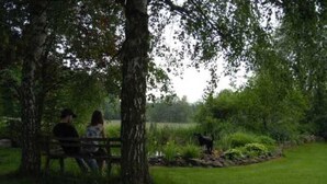 A park bench with two people sitting under a tree. - Room 7 - House by the forest (Lichtenfels)