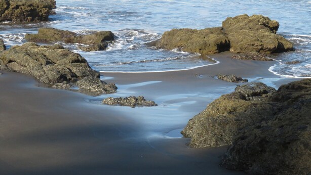 Una playa rocosa con olas rompiendo en la orilla.