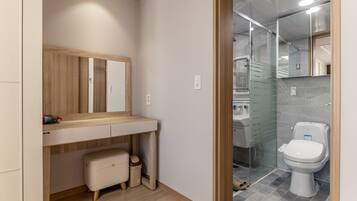 Een moderne badkamer met een houten wastafelmeubel, een spiegel, toilet en douche.