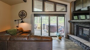 A living room with a fireplace, a large window, and a ceiling fan. - New Venture- 3BR Cabin by Terry Peak (Lead)