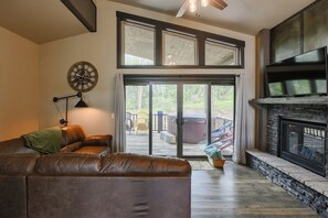 A living room with a fireplace, a large window, and a ceiling fan.