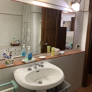 Ein Badezimmer mit einem weißen Waschbecken, einem Spiegel und einem Holzschrank.