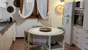 A compact kitchen with a dining table, chairs, a refrigerator, and a stove. - 2 steps from the sea of the Gulf of Carini (Carini)