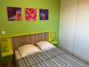 A bed with a striped bedspread, a wooden headboard, and two bedside tables with lamps.