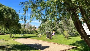 Un parc avec un terrain de croquet, des arbres et une aire de jeux.