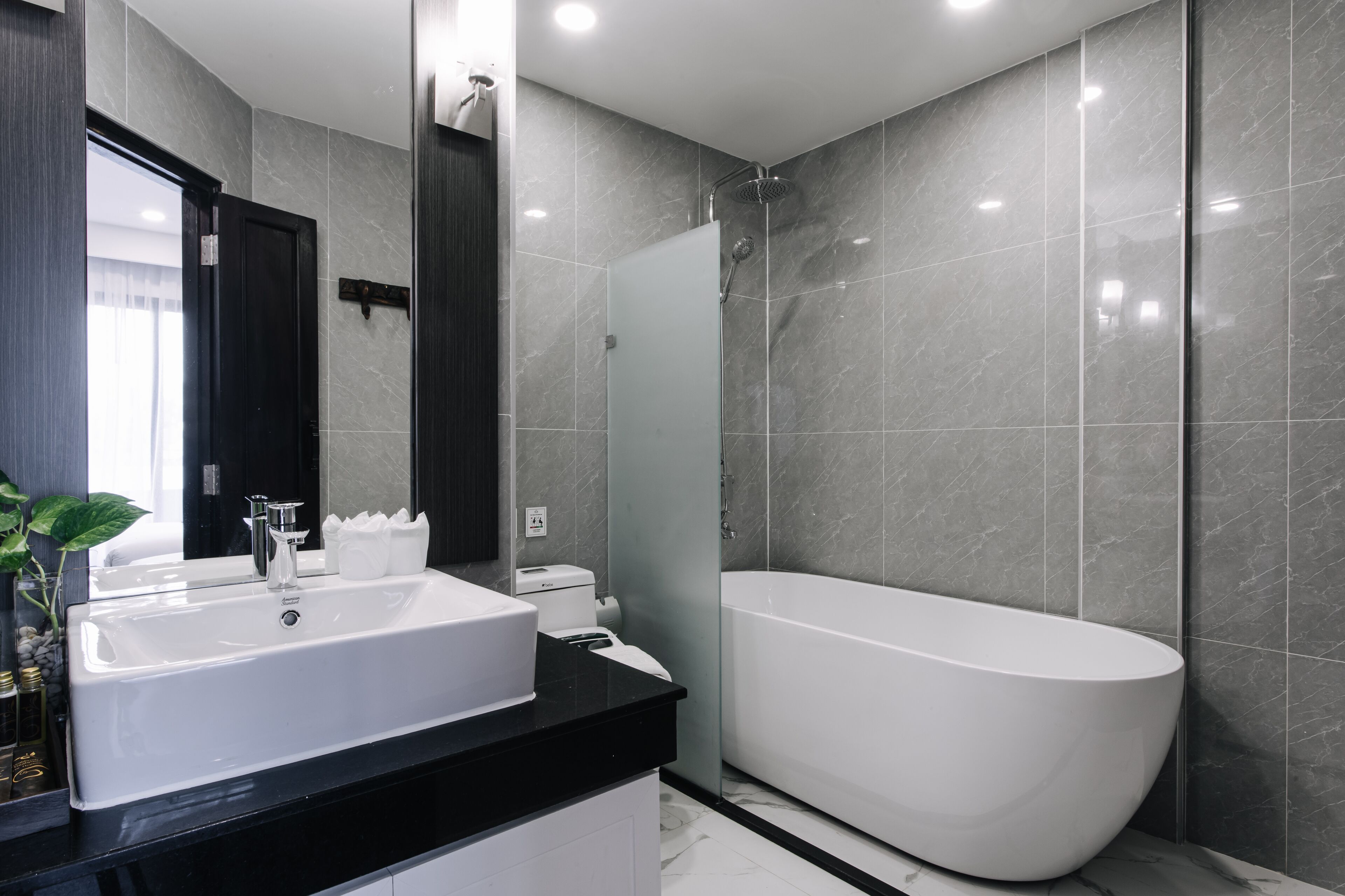 A modern bathroom with a large white bathtub, a double sink vanity, and a large mirror.