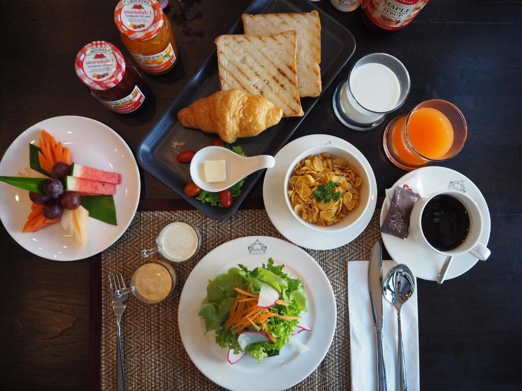 Desayuno con tostadas, croissant, fruta, ensalada, cereal, café y jugo.