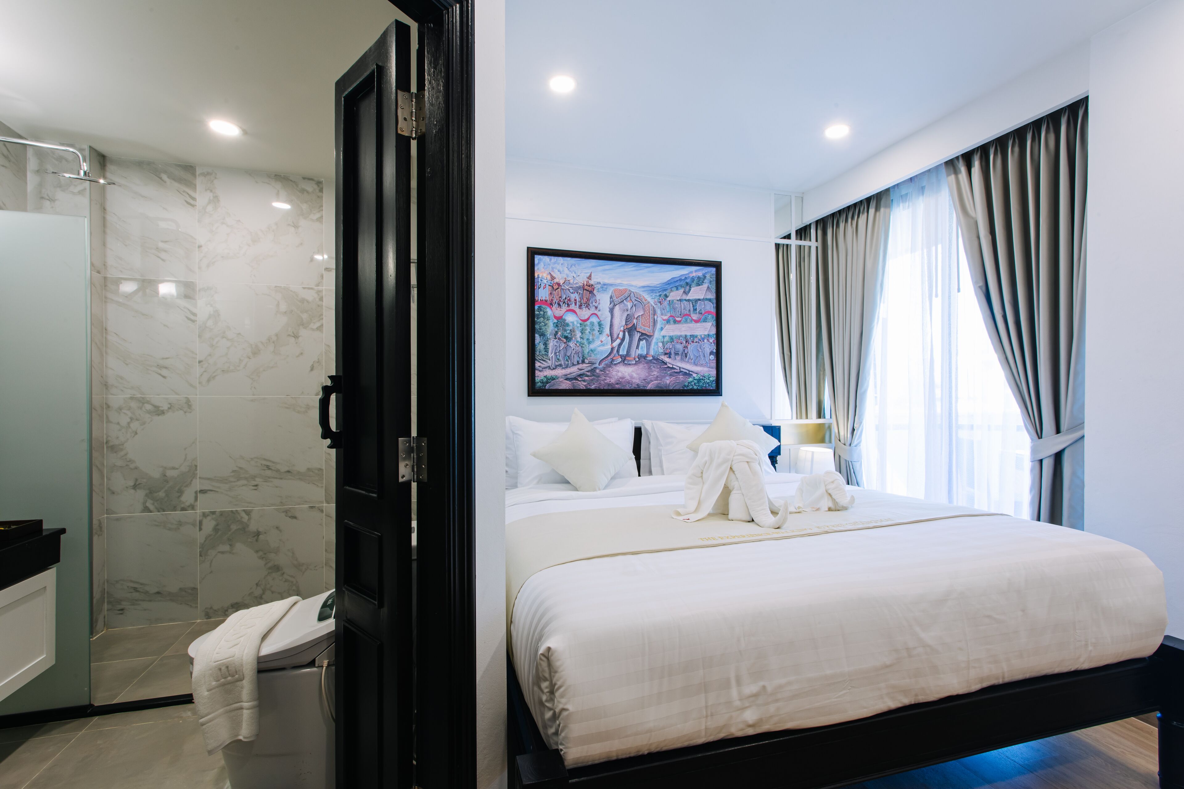 Une chambre d’hôtel moderne avec un grand lit, un espace douche et un tableau au mur.