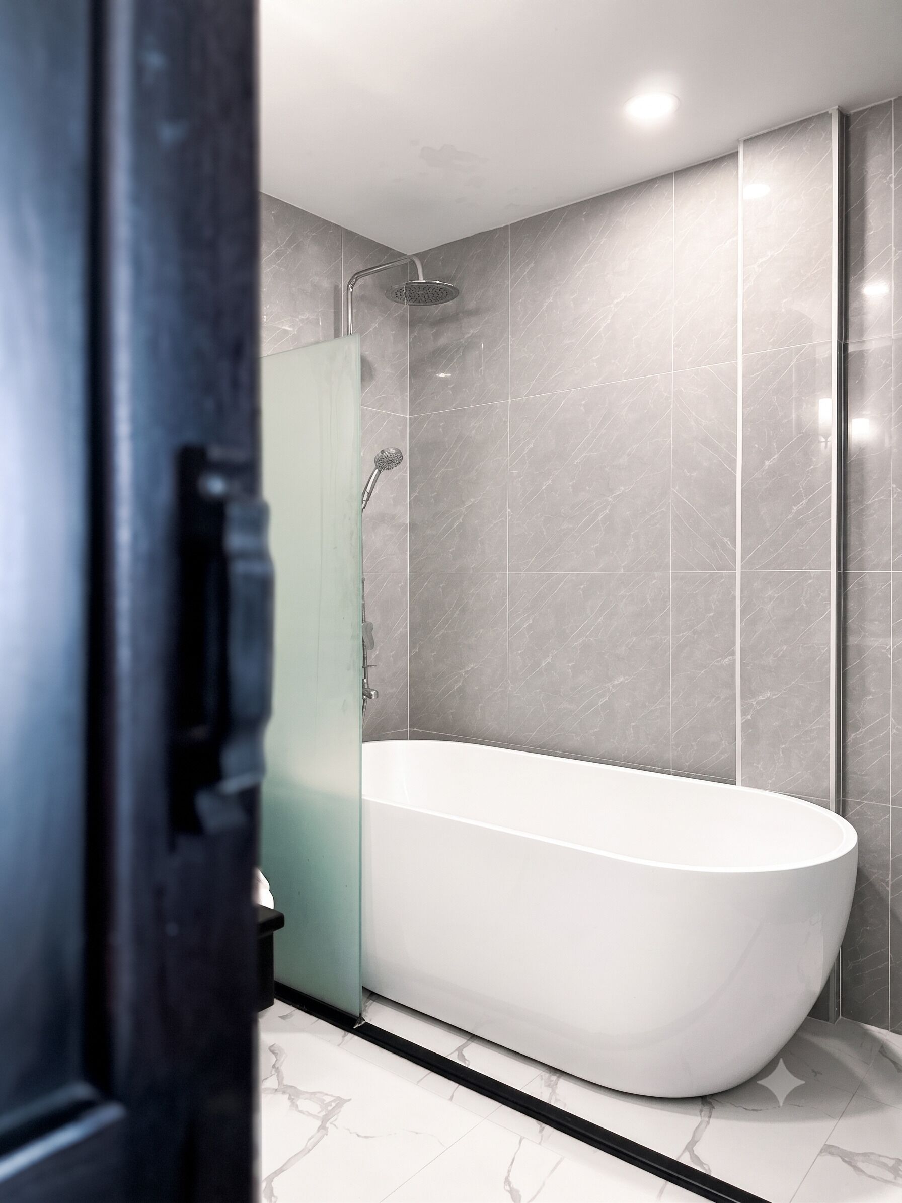 Ein modernes Badezimmer mit einer freistehenden Badewanne, einer Duschbrause und einer Glasdusche.