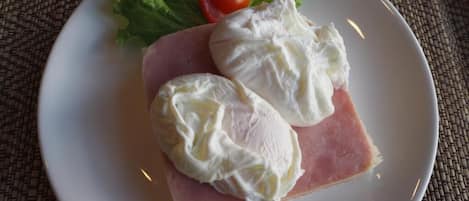Un plato con una loncha de jamón y dos lonchas de queso, acompañado de un tomate pequeño y lechuga.