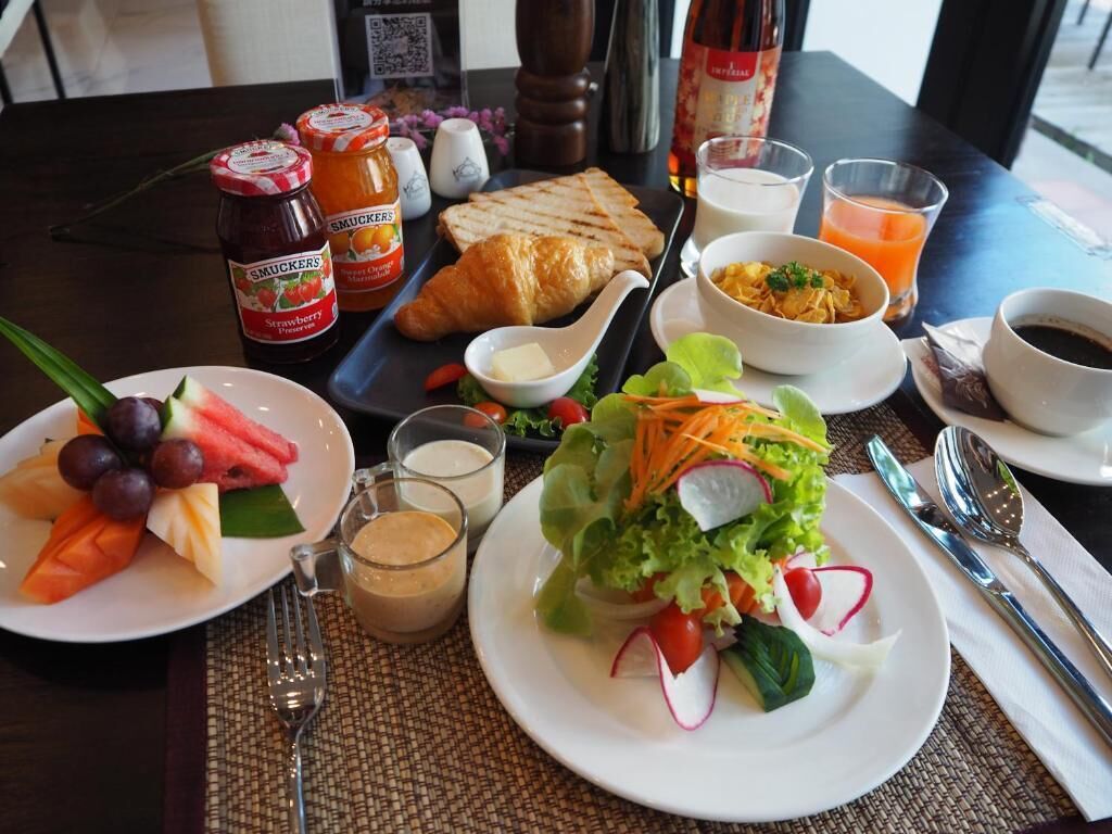 A breakfast table with croissants, fruit, a salad, and beverages.