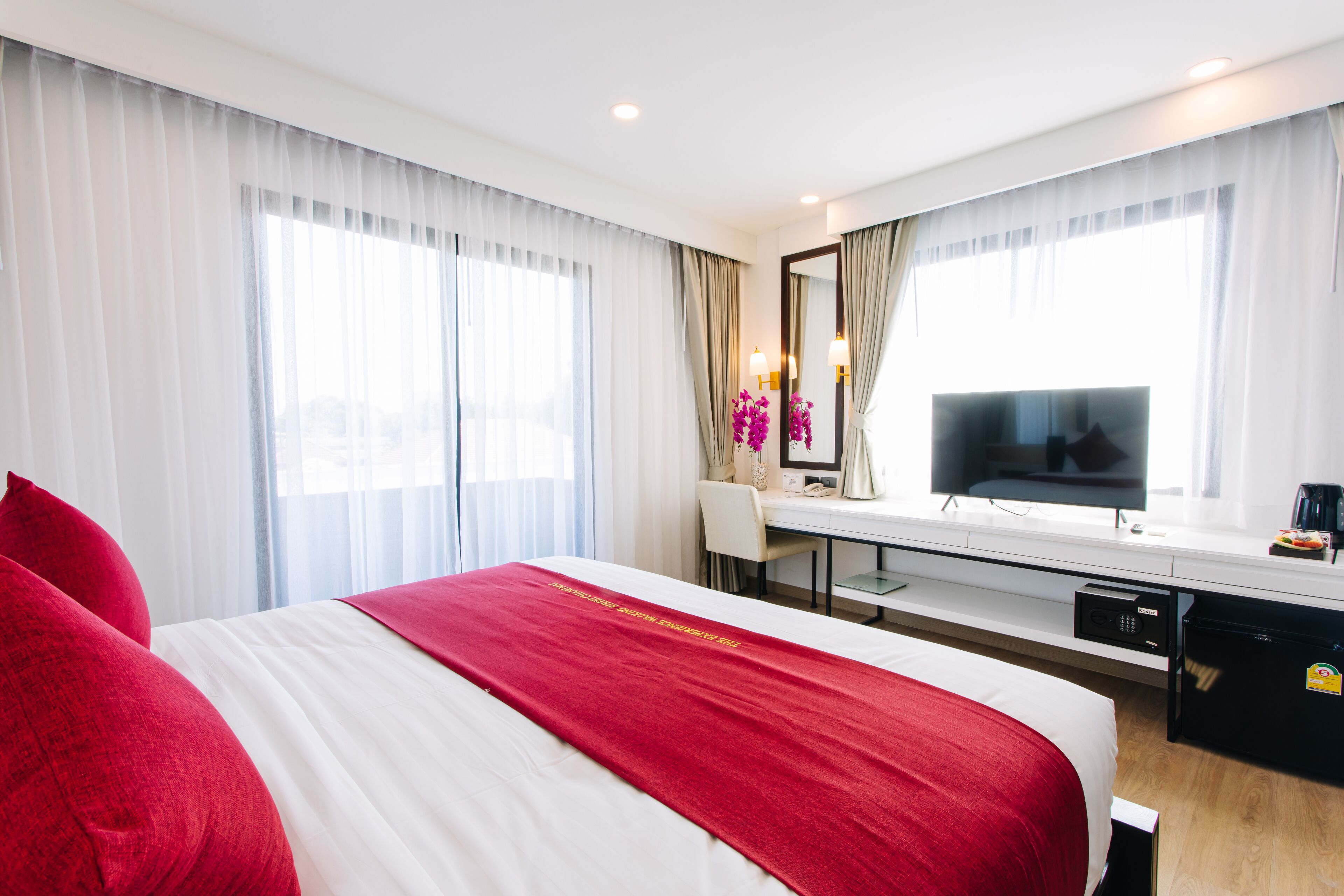 Una habitación de hotel con una cama grande, un escritorio con computadora, televisor y minibar.