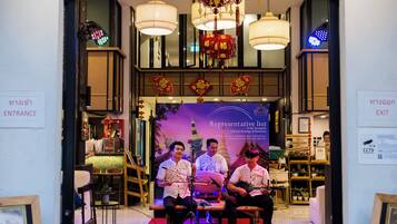 The entrance of 'The Experience' hotel and restaurant with a red carpet, chandeliers, and a 'Representative list' banner.
