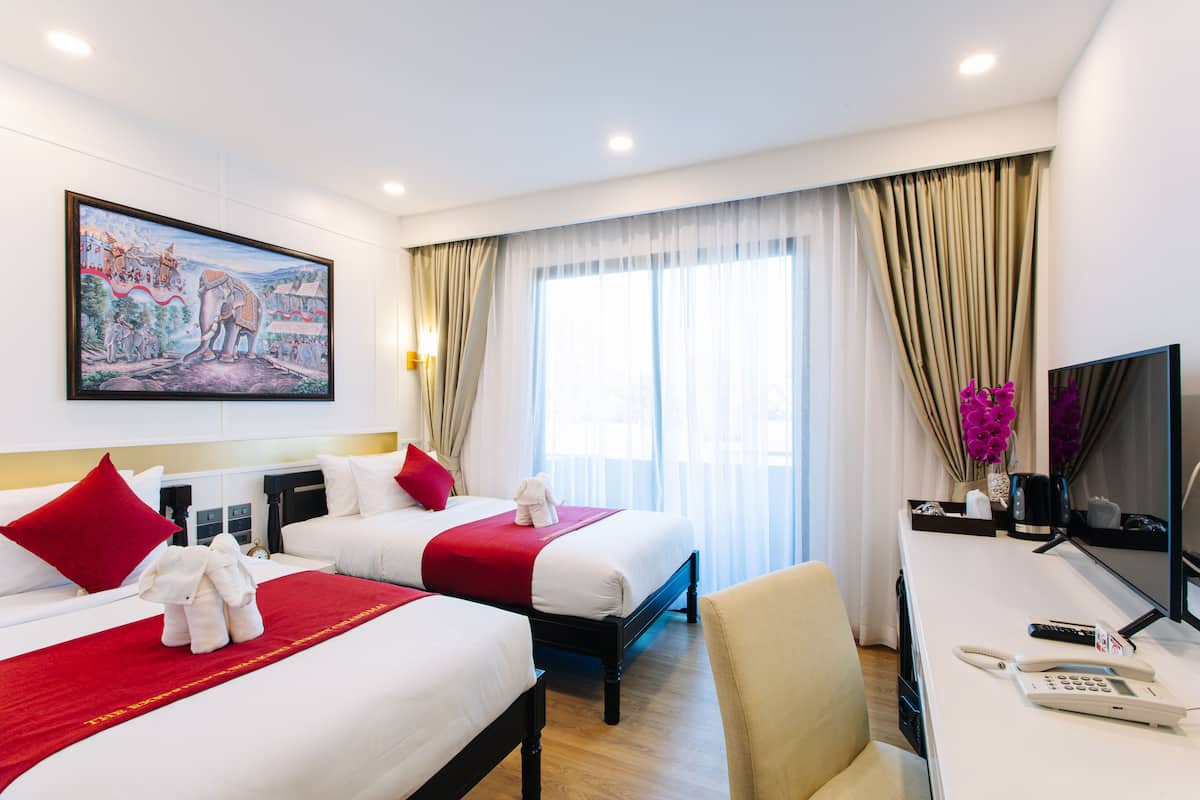 A hotel room with two beds, a desk with a phone, a TV, and a painting on the wall.