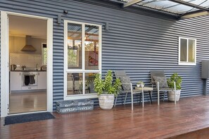 Een modern huis met een keuken, een terras met stoelen en plantenbakken, en een groot raam.