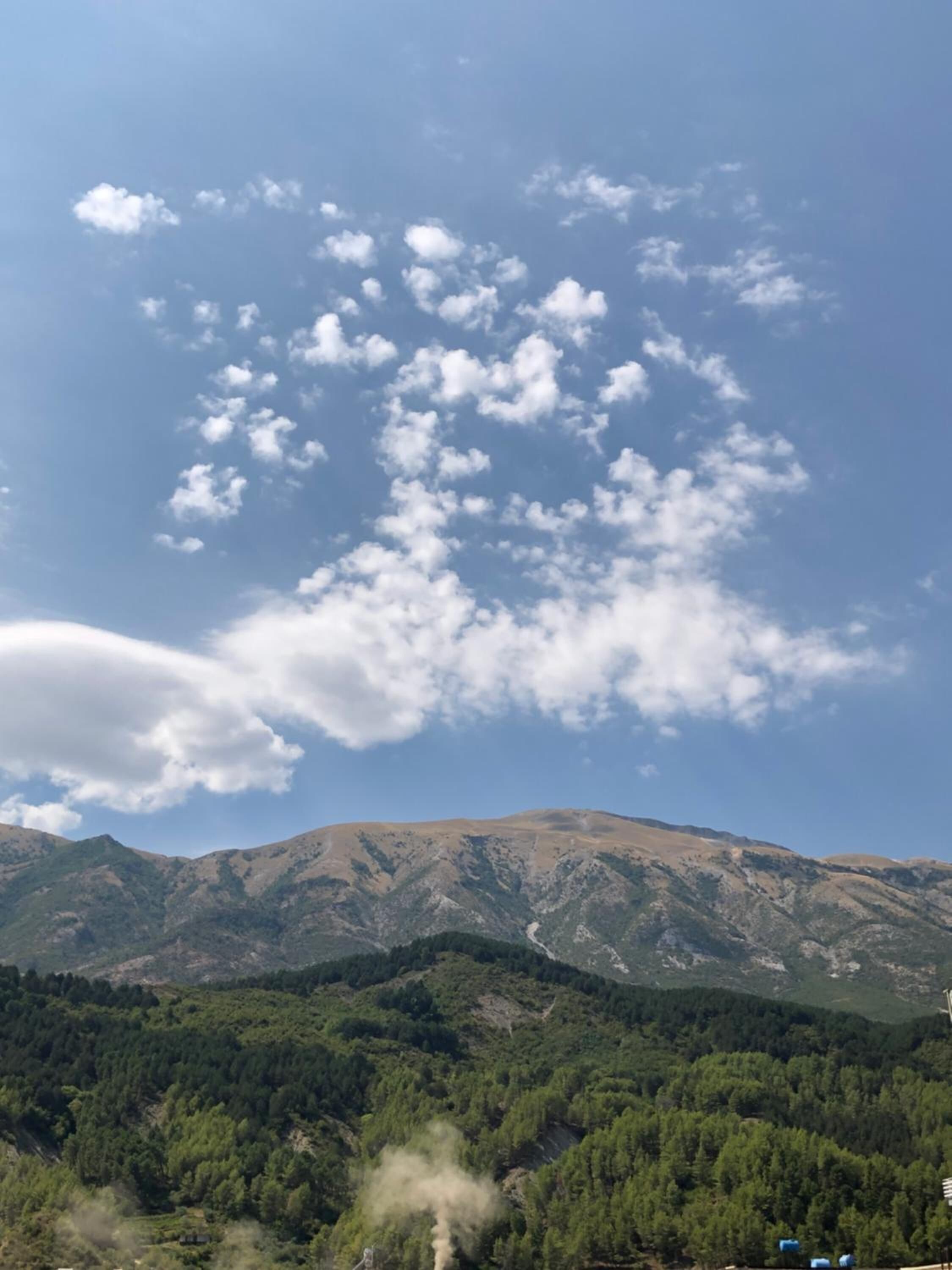 Un paisaje montañoso con cielo despejado y nubes dispersas.