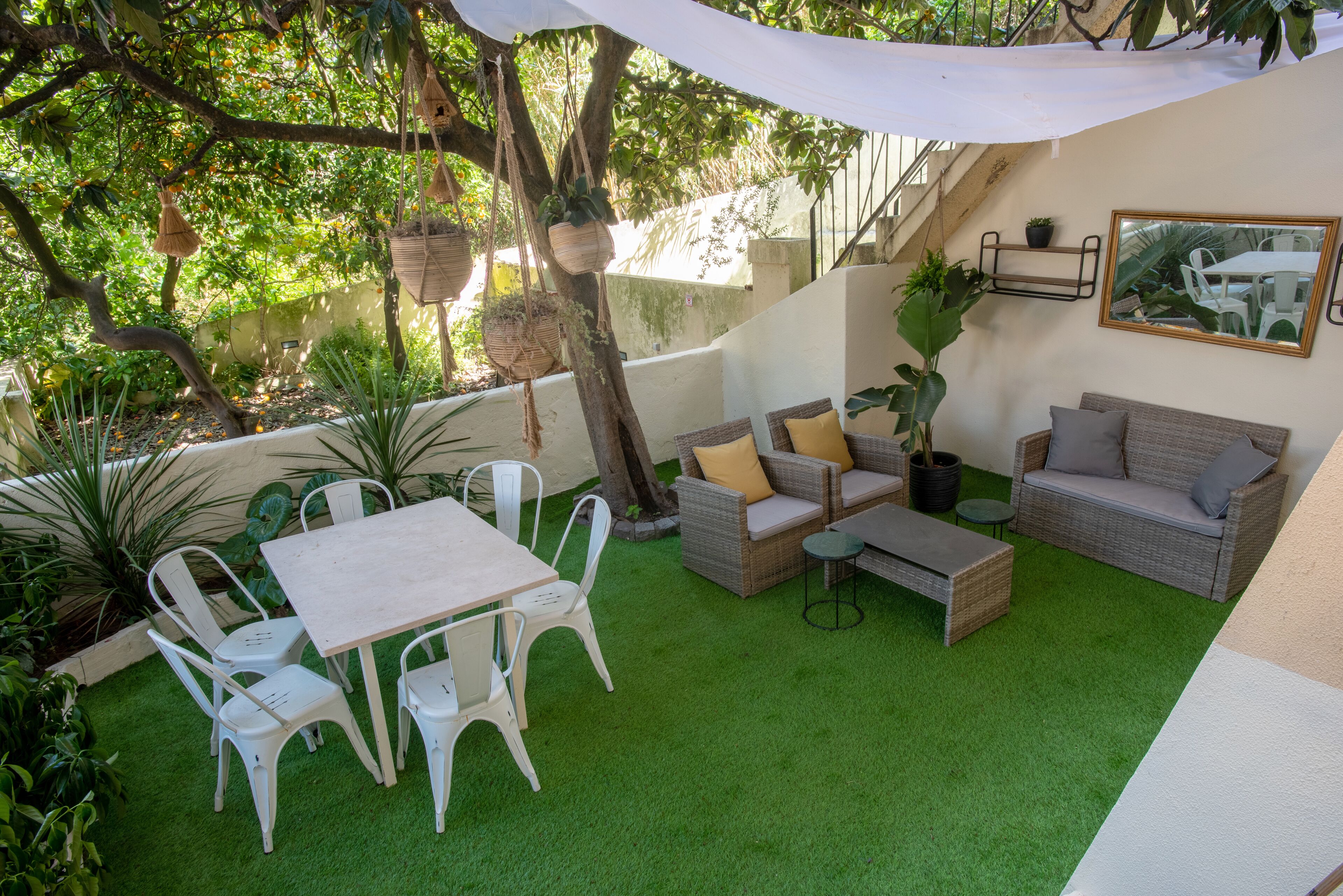 Un patio con una mesa y sillas blancas, sofás de mimbre y una pequeña mesa redonda.