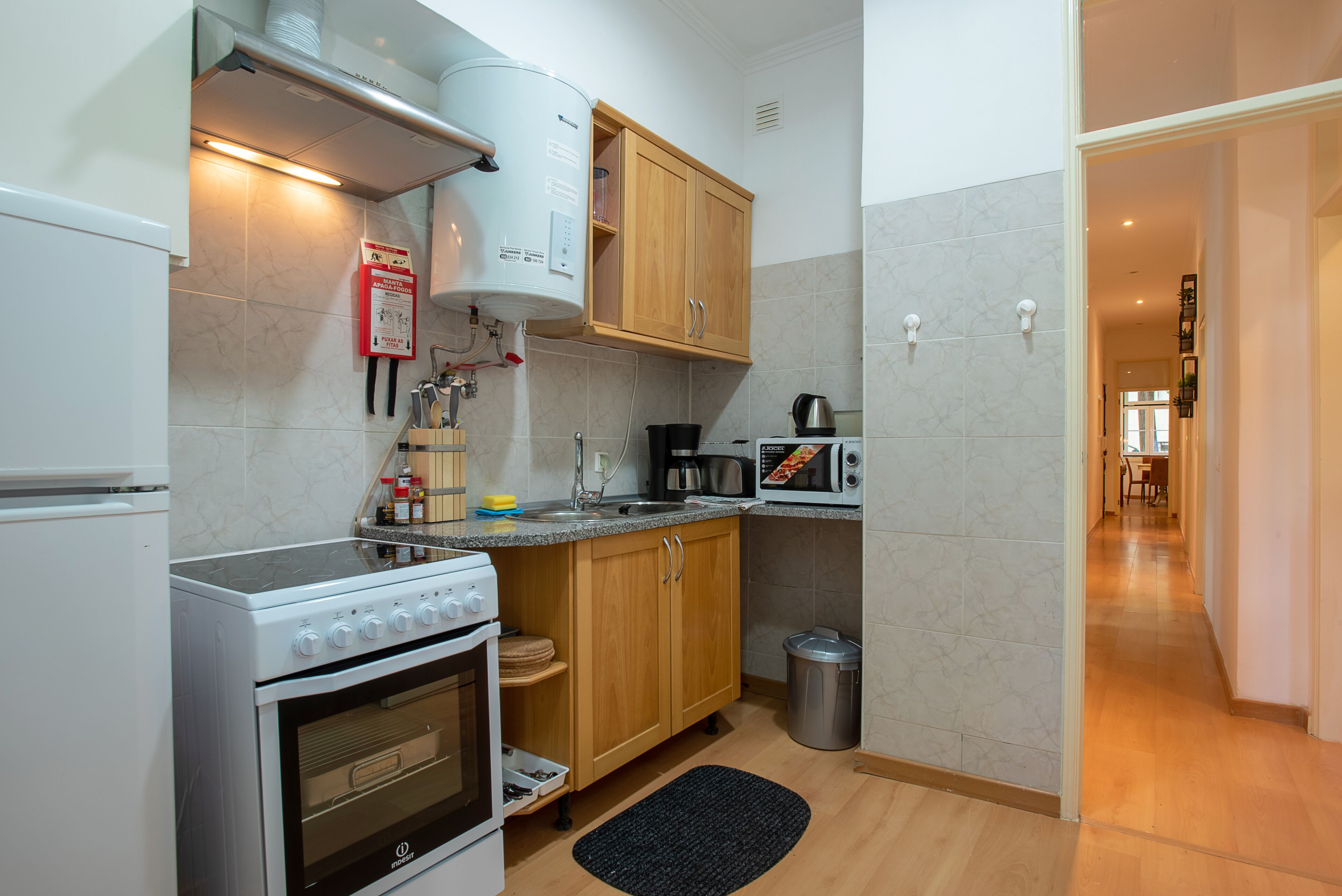 Una cucina compatta con fornelli, forno a microonde e pensili in legno.