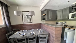 A modern kitchen with grey cabinets, a microwave, and a coffee maker. There is a dining area with a table set for four, including plates, glasses, and cutlery. - La Valériane 10 - Beautiful 3 room apartment, beautiful view on the mountain (LES AVANCHERS VALMOREL)