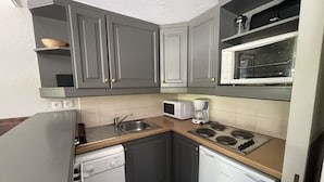 A compact kitchen with grey cabinets, a microwave, a coffee maker, a dishwasher, and a refrigerator. - La Valériane 10 - Beautiful 3 room apartment, beautiful view on the mountain (LES AVANCHERS VALMOREL)
