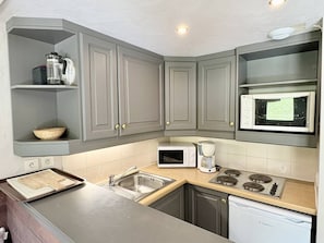 A kitchen with grey cabinets, a microwave, a coffee maker, and a dishwasher.