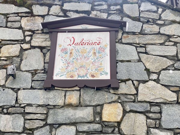 Eine Steinsäule mit einem Rahmen und einem Schild, das „Valeriane“ zeigt, sowie floralen Zeichnungen.