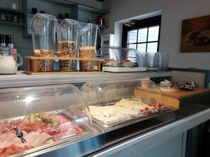 A buffet area with various food items, including meats and cheeses, displayed in clear containers.