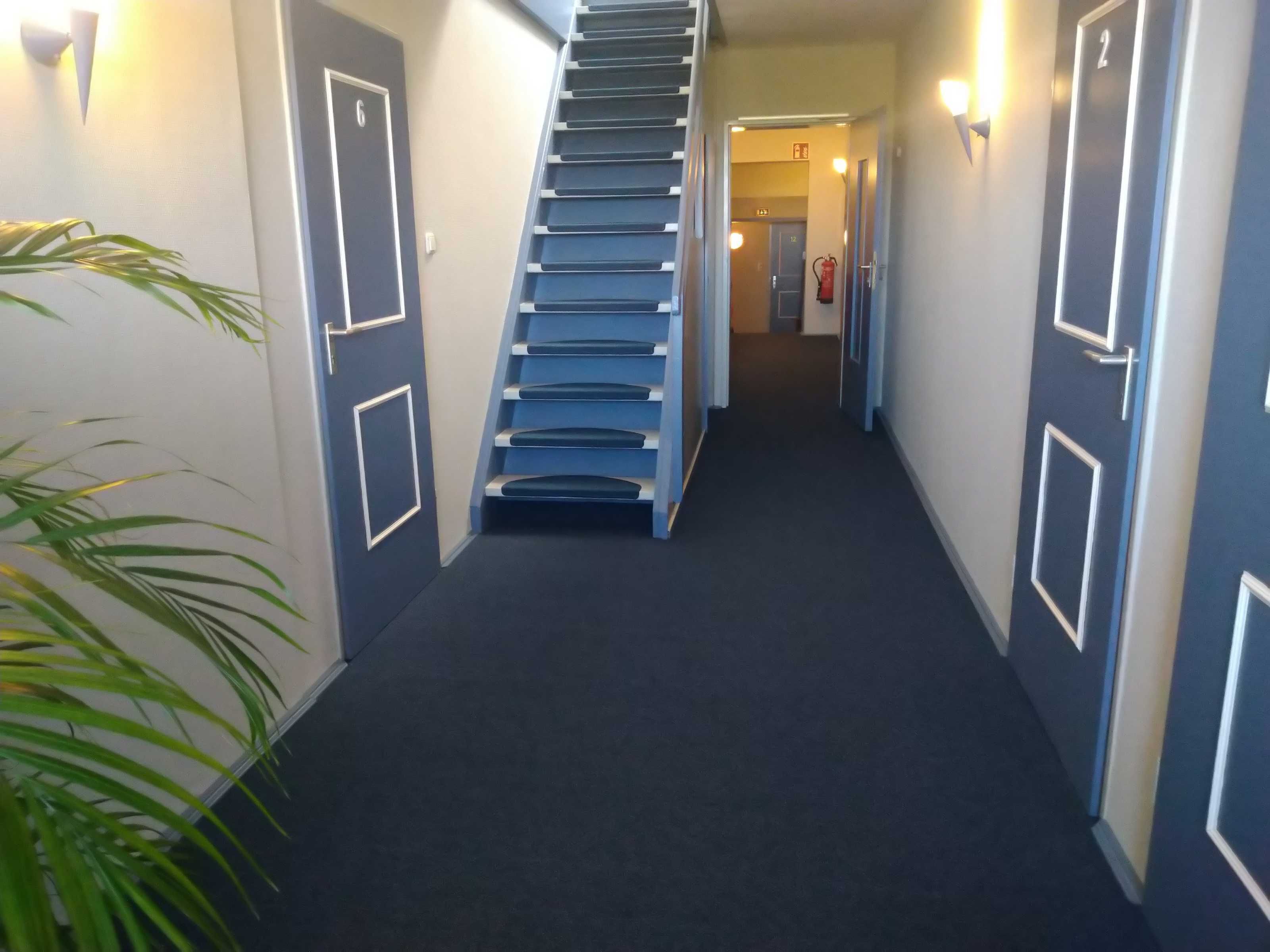 A hallway with a staircase leading to a door marked with the number 6.