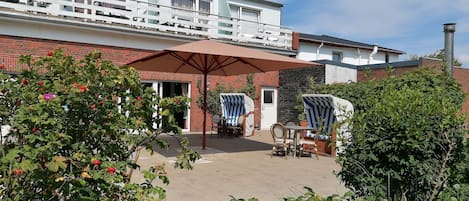 Une maison à deux étages dotée d’un balcon, d’une terrasse avec mobilier d’extérieur et d’un jardin planté d’arbres fruitiers.