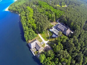 Luchtbeeld van een kustbezit met meerdere gebouwen, een pier en een bebost gebied.