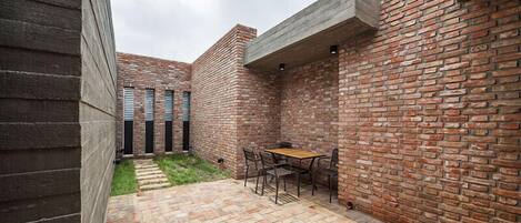 A patio area with a brick wall, a wooden table, and chairs.
