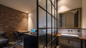 A modern bathroom with a large mirror, a sink, and a window with frosted glass panels. - Hotel March (Daejeon)