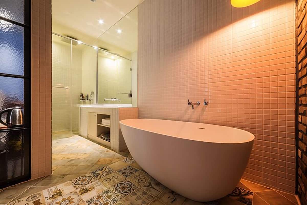 A modern bathroom with a freestanding bathtub, a glass shower enclosure, and a tiled backsplash.