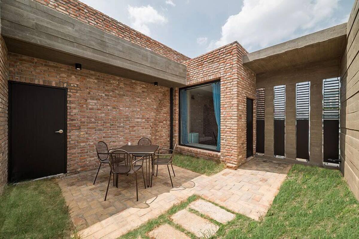 A patio area with a brick wall, a black door, and a table with chairs.