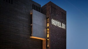 A modern hotel facade with a prominent 'HOTEL' sign on a textured brick wall. - Hotel March (Daejeon)